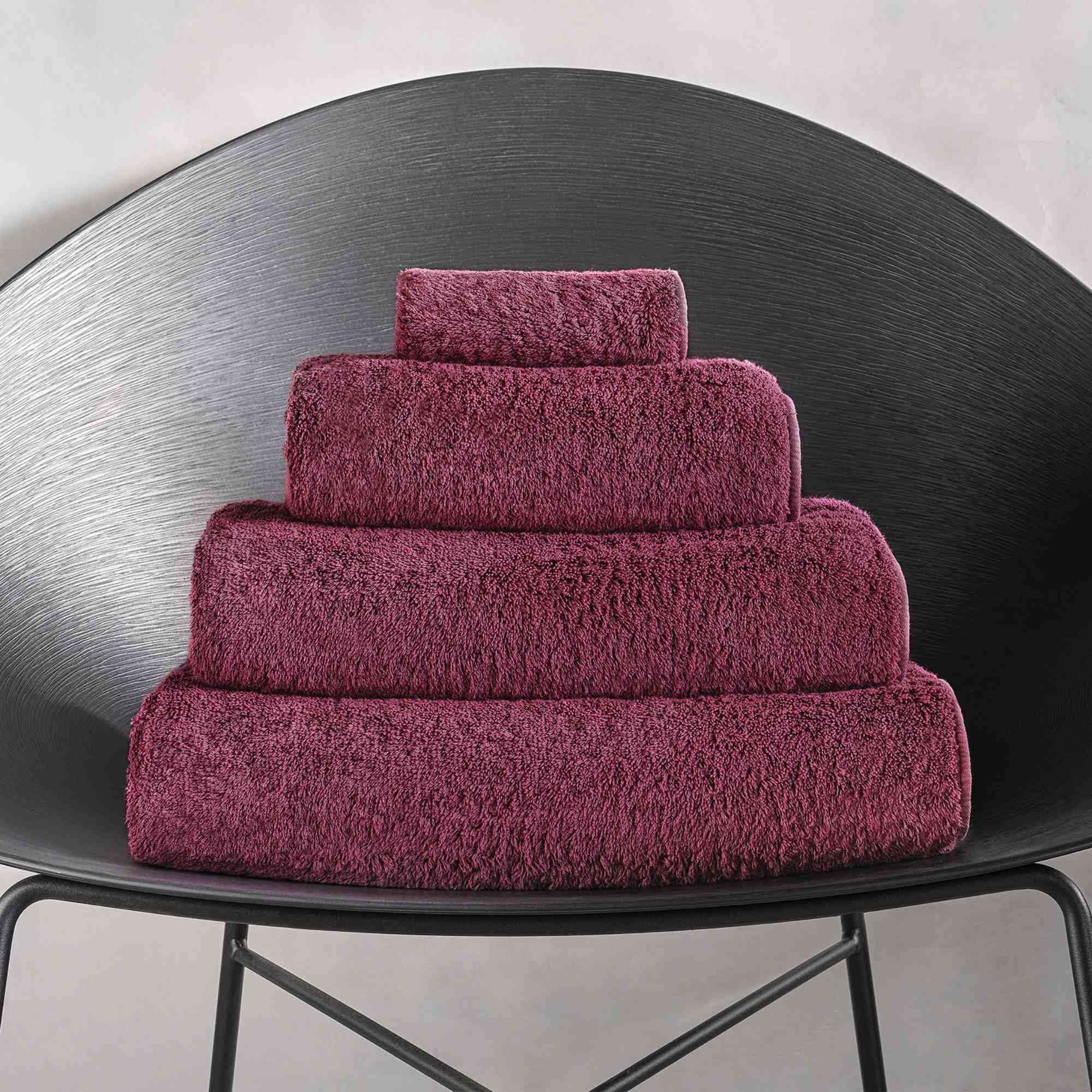 Stack of purple towels on a black chair against a light gray background.